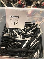 Plastic container filled with numerous black and white Lego Technic connector pins, showing quantity and item type