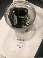 Clear plastic container holding various Lego Robotics gears and parts in black, gray, and beige colors.