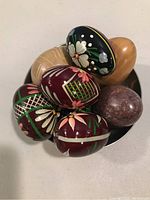 Close view of all eggs in pewter dish showing detailed hand painted designs and natural materials