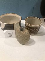Photo showing 2 ceramic pots and 1 vase on a white surface with blue background