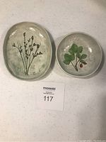 Oval and round ceramic plates with botanical designs shown together.