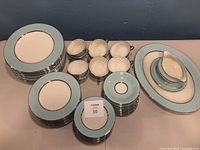 Overview of entire china set arranged: stacks of plates, cups with saucers, gravy boat and platter visible