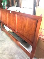 Full view of the solid cherry king-sized headboard showing the paneled design and reddish-brown finish.
