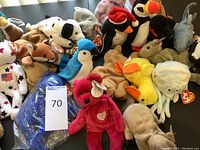 Photo showing a variety of Beanie Babies including a red bear with heart, Dalmatian and ducks, highlighting the plush's condition and variety.