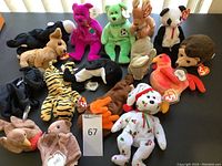 Photo showing full assortment of 15 assorted Ty Beanie Babies plush toys in various animal designs and colors, all arranged on a flat surface with tags visible on many.