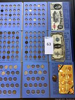 Photo showing multiple blue coin folders containing Mercury dimes and some loose pennies, with vintage paper currency laid around.