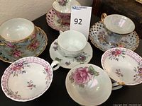 Overview photo of all 7 tea cup and saucer pairs with different floral designs and colors