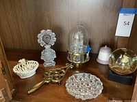 Full shot of the collection including crystal perfume bottle, metal trivet, swan decor, snow globe, porcelain bell, and glass trinket dish