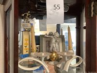 Wide shot of the top shelf showing the candlesticks, trophy, cherub figurine, and decorative elements