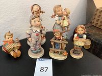 Full set of six Hummel child figurines arranged on a table, showing all items together.