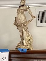 Front view of entire lady statue showing pose, floral garland, and base detail.