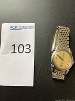 Full view of watch alongside lot number card on black background