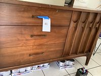 Front view showing three drawers on left with metal pulls and right cabinet door with sculpted pattern