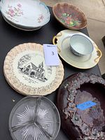 Full lot view showing all plates, pottery dish, glass divided dish, cup, and bowls arranged on a table.