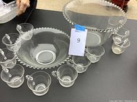 Overview of two clear glass punch bowls and ten matching cups arranged around them on a black surface.