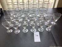 Full overview of 21 clear glass stemware pieces with silver rims laid out on table