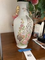 Full view of the ceramic vase showing peacock and flower design with gold handles