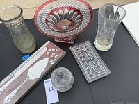 Overall lot view showing red and clear glass planter, two clear glass vases, plated server in box, and small clear glass covered dish arranged on black surface.
