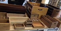 Overview of more than a dozen assorted wooden boxes of different sizes and colors arranged on a table