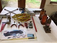 Photo of automotive tools including jacks, jumper cables, multimeter, lug wrench, and solar panel packaging.