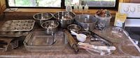 Full overview of baking items on countertop including muffin tins, pie pans, mixing bowls, baking dishes, spatulas, whisks, and cookie cutters