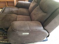 Close-up of the chocolate brown dual electric reclining love seat showing cushioned armrest and upholstery texture.