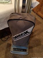 Photo of the Oreck XL upright vacuum cleaner, showing grey cloth bag with Oreck logo and base with Oreck XL labeling.