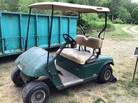 Side view of green two-seat EZGO electric golf cart with canopy.