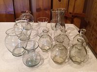 Photo showing all 11 glass vases arranged on a white cloth-covered surface, highlighting variety in shape and size.
