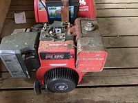 Close-up of the red 8 HP Industrial Plus engine showing pull start and gas tank area, engine has visible dirt and wear.