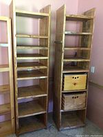 Full view of two tall handmade pine shelving units side by side, showing open shelves and wooden storage cubes in one unit.