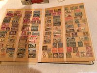 Open stamp album pages showing rows of various stamps attached on cream colored pages under protective sleeves.