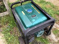 Side perspective showing green fuel tank, black metal frame, and two wheels; unit placed on grass ground outdoors.
