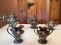 Five-piece silverplate tea service displayed on table (coffee pot, teapot, sugar bowl, creamer, slop bowl)