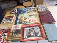 Overview of the full book lot arranged on a wooden table showing 9 vintage children's books of various sizes, colors and illustrations.