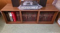 Three wood cube shelving units side by side holding record albums with a turntable and speakers above. Medium brown wood grain finish visible.