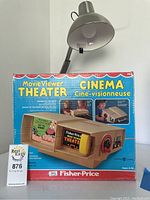 Front of box showing Fisher-Price Movie Viewer Theater with cartoon reel, colorful and detailed packaging.