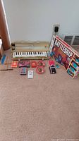 Full view of all items including Suzuki melodian keyboard, Battleship game box, Japanese wooden tops and propeller toys, and playing cards arranged on floor