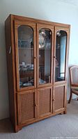 Front view of six-door wooden hutch with glass upper doors and cane lower doors.