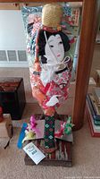 Full view of the ceremonial Japanese Hagoita paddle with fabric female figure, colorful kimono, and ornamental straw hat, mounted on wooden base with floral decorations.