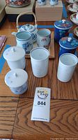 Assorted Japanese porcelain including teapot, tea cups, and small lidded containers displayed on wooden table