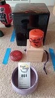 Photo showing the black lacquered tiered box, orange bento box, small red lacquered box, and purple ceramic bowl in wooden box