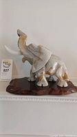 Front left angle view of the marble elephant figurine showing trunk raised, tusks, and wooden base.