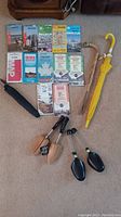 Overview of the lot showing 10 assorted road maps, two umbrellas (one yellow, one black), and two wooden shoe forms.