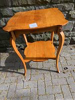 Full view of bird’s eye maple wood side table with curved legs and lower shelf, showing overall design and condition under daylight.