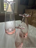 Three light pink hand-blown glass vases displayed on a marble surface with natural window light highlighting bubble inclusions and clear to pink gradient.