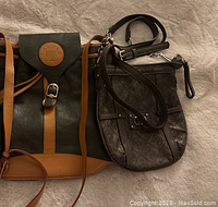 Two designer purses laid on surface, black Lanvin purse with tan accents and brown Guess purse with monogram pattern visible