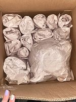 Box containing multiple wrapped items packed in brown paper for protection