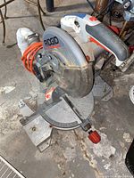 RIDGID brand power miter circular saw showing blade, base, handle, and orange power cord on the floor.