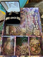 Overview of assorted jewelry pieces in floral box with some in Geneva branded box